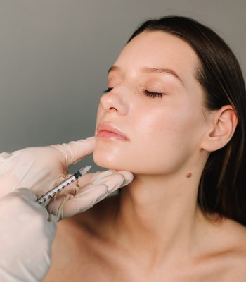 Cosmetologist making filler injection in female chin. Improving the shape of the chin by high quality doctor. Beauty treatment of face correction